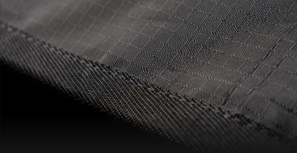 Close-up of the black ripstop outer fabric and taped edge of a board bag