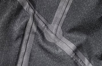 Close-up of taped seams meeting on grey technical fabric
