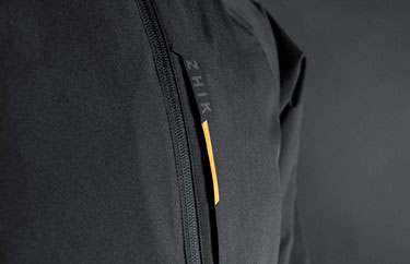 Close-up of a black Zhik jacket showing a vertical zip and a yellow trim detail