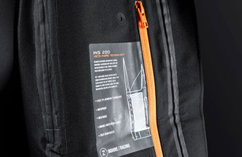 Swing tag describing waterproof fabric technology hanging beside the orange zip of a black jacket