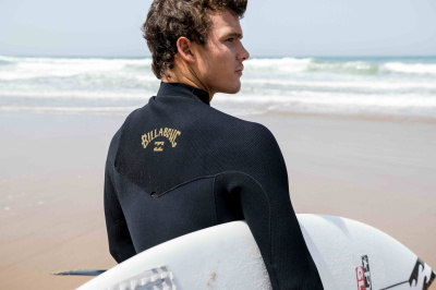 uomo in spiaggia con una muta Billabong