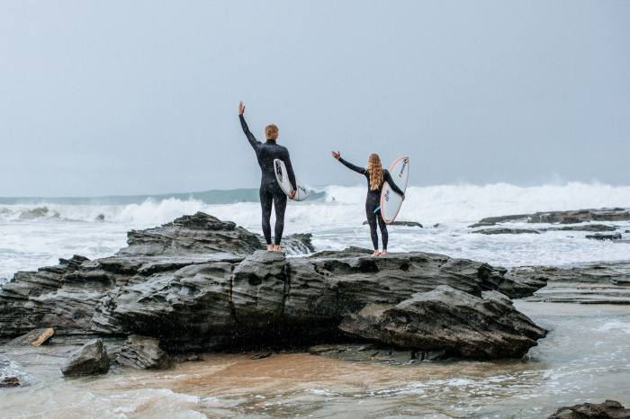 Surfista con una muta Rip Curl Trad che entra in acqua con la tavola
